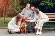 © hetmanstock2 - Family in a summer park. People sitting with a dog. Parents with a two daughters