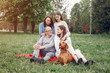 © hetmanstock2 - Family in a summer park. People sitting with a dog. Parents with a two daughters