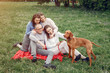© hetmanstock2 - Family in a summer park. People sitting with a dog. Parents with a two daughters