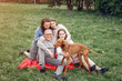 © hetmanstock2 - Family in a summer park. People sitting with a dog. Parents with a two daughters