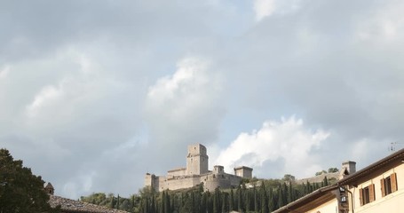 Wall Mural - Panorama of the Rocca Maggiore castle in Assisi. The fortress illuminated at sunset immersed in a cypress wood.