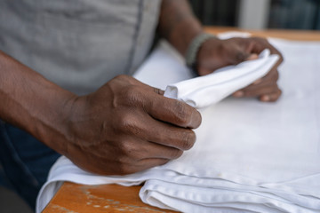 Wall Mural - Waiter folds napkins in restaurant. Waiters hands with white napkin closeup