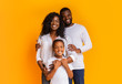 Happy Family Of Three Hugging And Posing Over Yellow Background