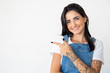 Smiling young woman pointing to left. Positive lady showing empty copyspace on white background. Concept of indication
