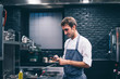 © Jes˙s Martinez/Westend61 - Chef using smartphone in the kitchen, of a restaurant