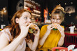 © KNSY/Westend61 - Two female friends eating burger in a restaurant