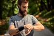 © Dangubic/Westend61 - Portrait of sporty man with earphones in forest checking his smartwatch