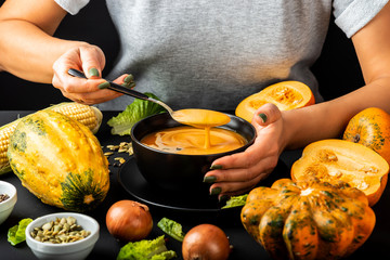 Wall Mural - Woman tasting homemade pumpkin cream soup. Vegetarian healthy diet food concept.