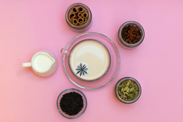 Milk tea masala chai with ingredients on pink background, top view