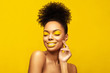 © Beauty Agent Studio - Excitement African American Fashion Model posing against yellow background and touch her face. Head shot portrait . Satisfied Brunette young woman with afro hair style and creative yellow make up