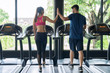 Young man and young woman in sportwear giving high five while exercising at the gym.