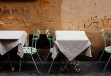 Chairs And Table Arranged Against Wall At Sidewalk Cafe