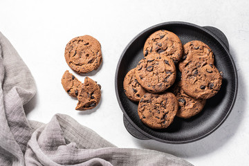 Fresh organic homemade chocolate cookies in black bowl on white marble table top view. Tasty homemade dessert close up.