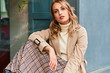 canvas print picture - Beautiful blond girl in stylish trench coat and skirt confidently looking in camera outdoor