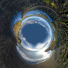 Inverted little planet of landscape of the black sand beach in Stokksnes on a sunny day. Vestrahorn mountain in the background. Fisheye distorted panorama.Nature and ecology concept background.