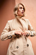 © Anton - Side view of stylish blond girl in trench coat thoughtfully looking away outdoor