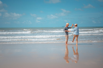 Senior couple dancing on the beach on good days, plan life insurance at retirement concept.