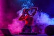 © ZaStock - Young sexy woman dj playing music. Headphones and dj mixer on table. Colorful Smoke on background