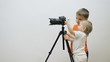 © MEDIAIMAG - Boy and little baby brother searching camera with tripod, teamwork discovery