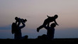 © MEDIAIMAG - Mother and father silhouettes lifting up baby and brother to sunset sky, parents