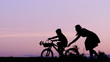 © MEDIAIMAG - Mother and son silhouette at sunset, parent help child to learn to ride bike