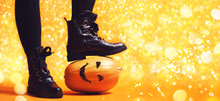 Legs Of Witch Standing On Scary Pumpkin.