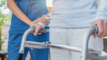 Cropped Image Of Nurse Helping Senior Woman To Walk With Walker At Home