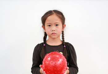 Wall Mural - Peaceful little Asian child girl holding round silicone inflatable red knobby ball on white background.