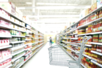 Supermarket aisle with empty shopping cart.