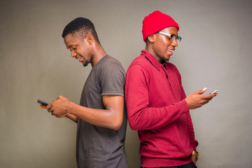 two men backing each other and holding operating cellphone