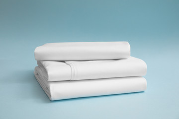 Stack of white bedding against blue backdrop,