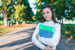 © byswat - Teenage girl schoolgirl, teenager white sweater summer city, background trees road, warm sweater, hands notebooks books and folders, smiling happy, after lessons school institute free space for text.