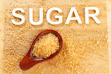 Wall Mural - Pile of cane sugar on wooden background, word sugar