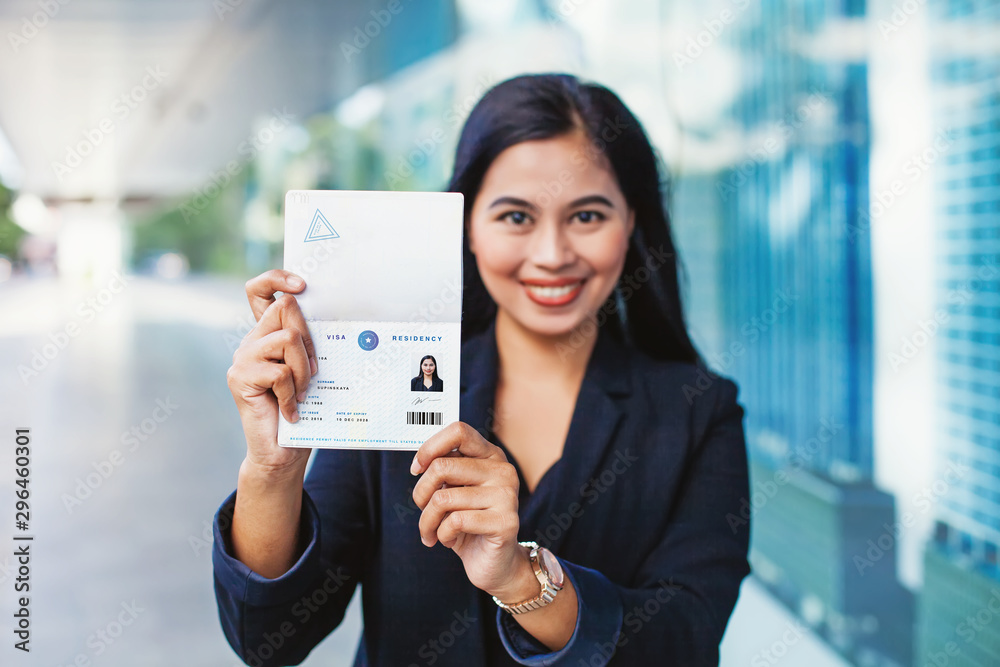 Asian woman showing valid visa and work permit in her passport - obrazy, fototapety, plakaty 