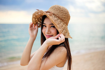 Beautiful girl young woman asia in a  hat smiling on the beach at sunset,enjoy summer vacation on the beach.