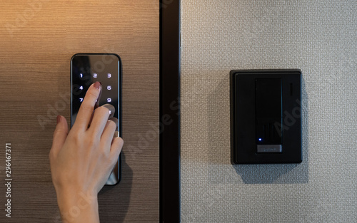 Closeup of a woman\'s finger entering password code on the smart digital touch screen keypad entry door lock in front of the room. Self Check-in, Airbnb, Modern security, Keyless, Temporary codes.