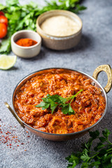 Wall Mural - Chicken meat with tikka masala sauce, spicy curry food in iron copper pot with seasonings