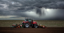 Beautiful Landscape With A Farmer Plowing His Fields Before The Storm