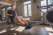 The athlete is engaged in the gym, the Young man works on the rowing simulator