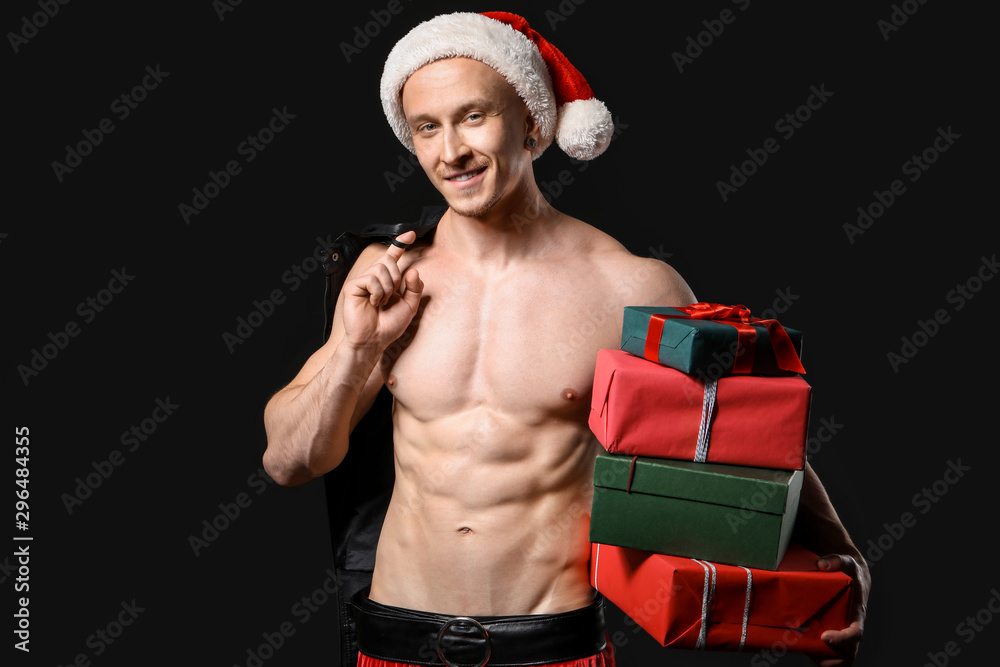 Young athletic Santa Claus with gifts on dark background