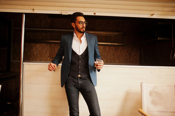 Wall Mural - Handsome well-dressed arabian man smoke cigar with glass of whiskey at balcony of pub.