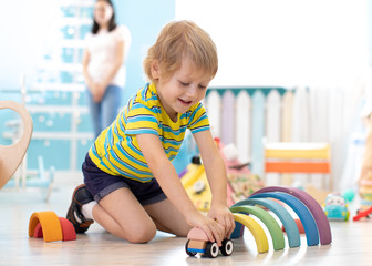 Poster - kid toddler playing wooden toys in daycare or kindergarten