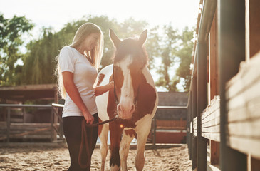 Happy woman with her horse on the ranch at daytime