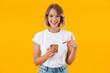 © Drobot Dean - Image of joyful blond woman smiling and pointing finger at cellphone
