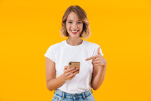 Image Of Joyful Blond Woman Smiling And Pointing Finger At Cellphone