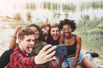 Wall Mural - Making photo. Group of people have picnic on the beach. Friends have fun at weekend time