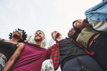 Wall Mural - Cheerful mood. Multi ethnic group of people have party outdoors. View from down