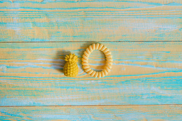 Flat lay of pineapple fruit toy on on blue and yellow wooden old background minimal creative concept. Silicone rubber band for hair. copy space. top view.