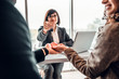 © HBS - Cropped image of happy family couple making purchase their first house, taking key from female realtor. View from behind the customers. Estate agency concept