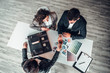 © HBS - View from above of group business people sitting on the table in office.Young couple in formal wear taking property keys from real estate agent. Sales agreement concept